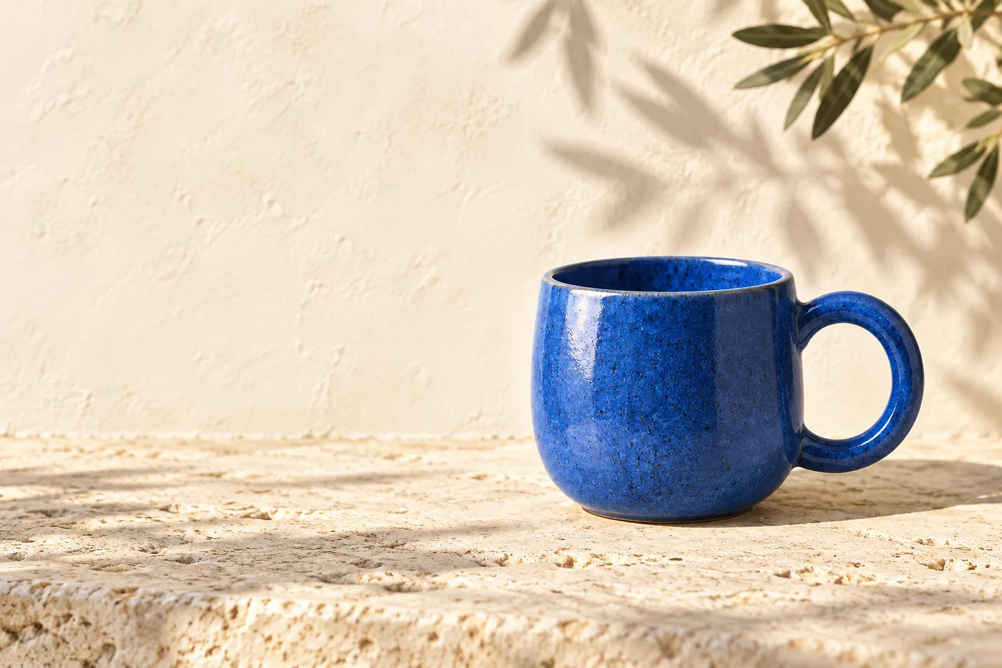 Blue ceramic cup on the right of a sunlit stone terrace, with an open cream background for a headline on the left